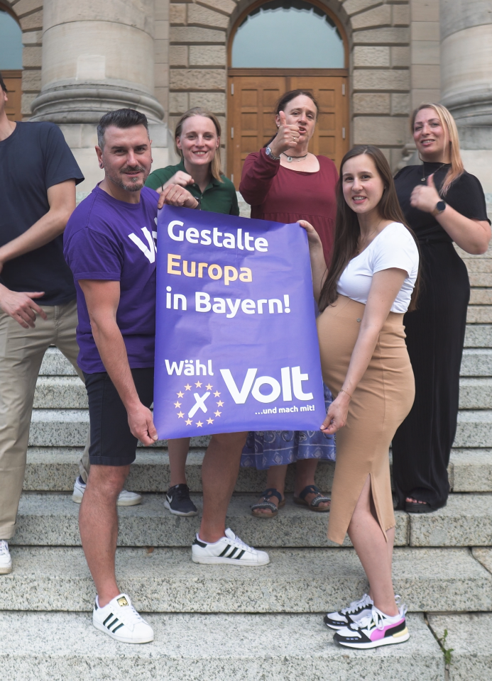 Gruppenbild von den Volt Bayern Mitgliedern die ein Wahlplakat hoch halten