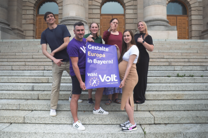 Gruppenbild von den Volt Bayern Mitgliedern die ein Wahlplakat hoch halten