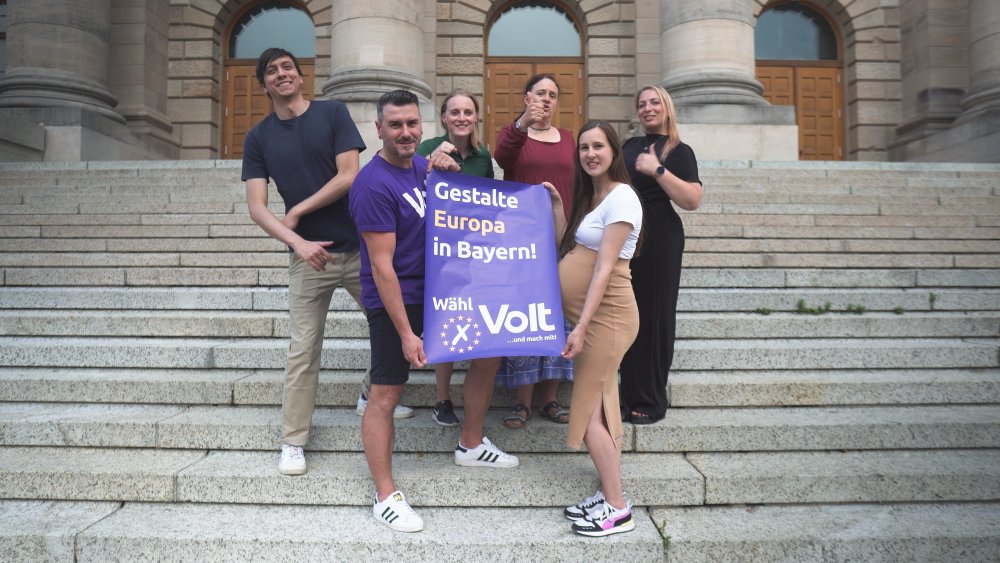 Gruppenbild von den Volt Bayern Mitgliedern die ein Wahlplakat hoch halten