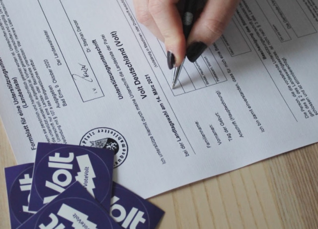 Foto eines Formulars, auf dem gerade eine Hand mit Stift eine Unterschrift setzt