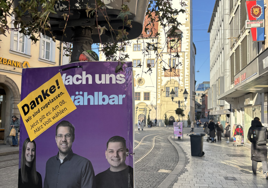 Ein Plakat von Volt hängt vor dem Rathaus: Zugelassen zur Stadtratswahl
