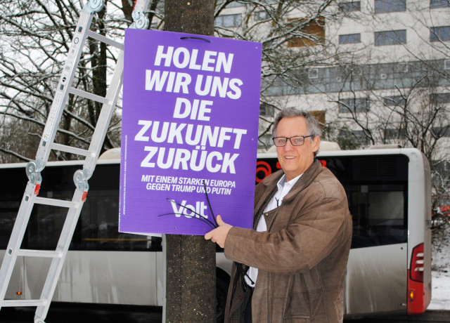 Thomas Peter, Direktkandidat für Bonn hängt ein Wahlplakat auf. Hinter ihm ein Bus der SWB. Foto: Kim Struckhof