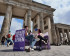 Damian Böselager sitzt vor dem Brandenburger Tor in Berlin auf einem Lila Sofa und stellt sich Fragen einer Bürger*in. Das Bild wurde mit KI vergrößert.