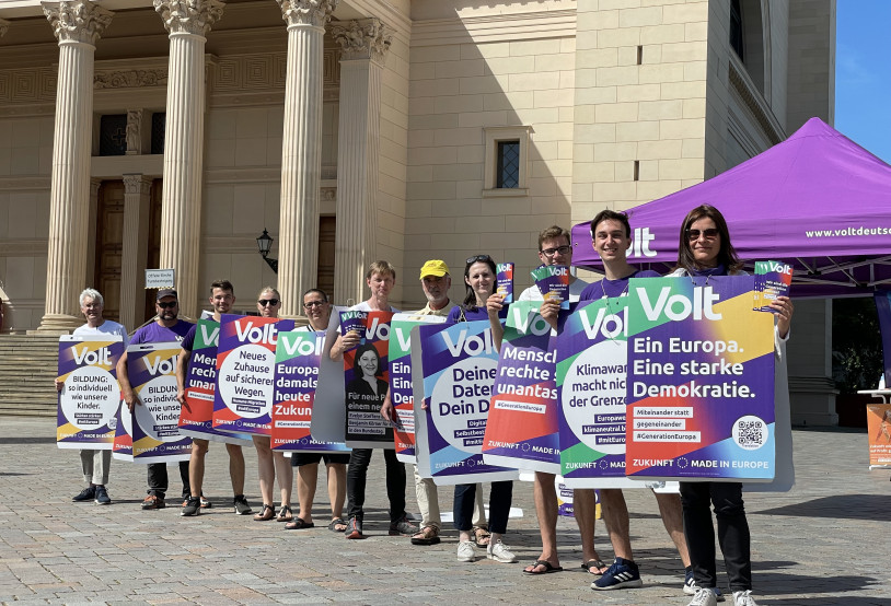 Menschen aus Volt Potsdam machen eine Plakat Schlange vor der Nicolai Kirche.