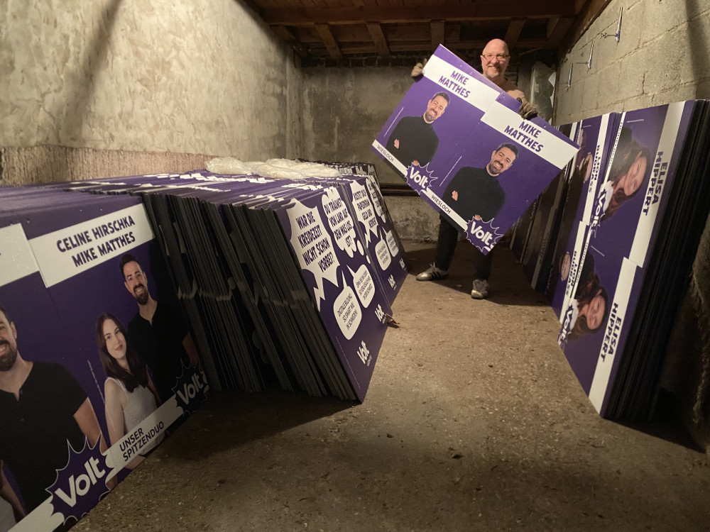 Viele Volt Plakate. In der Mitte ein Mann mit einem Direktkandidaten-Plakat in der Hand.