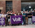 Viele Menschen aus dem Team Volt Heidelberg. Sie halten eine Volt Flagge und zwei Plakate vergangener Wahlen hoch.