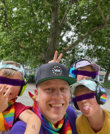 Bernhard mit Regenbogen-Halstuch und Volt Basecap mit Kindern um ihn.