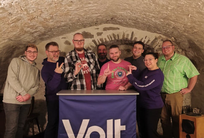 Volt Mitglieder stehen zusammen und zeigen mit den Händen 