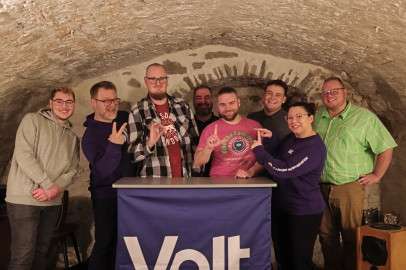 Volt Mitglieder stehen zusammen und zeigen mit den Händen "Volt"