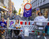 Auf einer gesperrten Straße spielen 3 Menschen eine lebendige Slot Machine und eine weitere Person steht hinter einer Zuckerwattemaschine