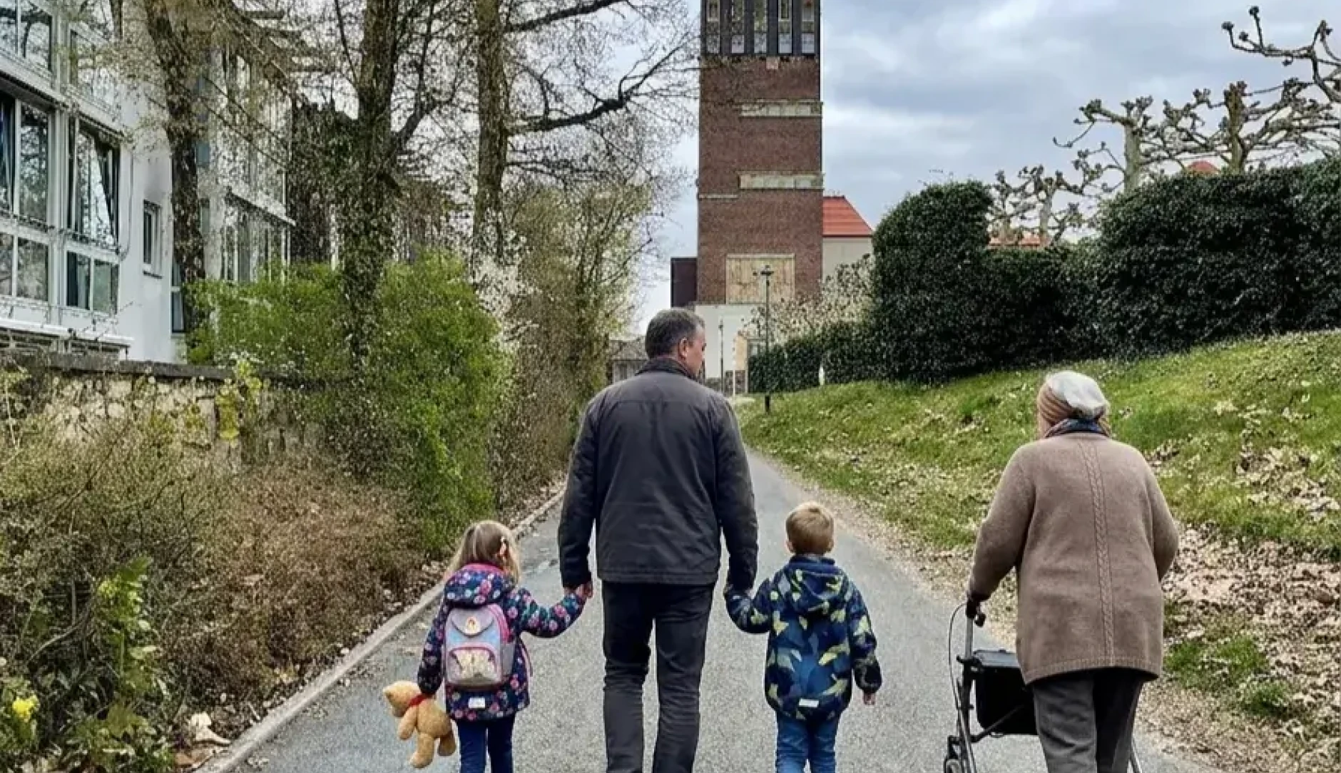 Bild einer Familie (Tocher, Vater, Sohn, Oma) beim Familienspaziergang, im Hintergrund der Hochzeitsturm auf der Mathildenhöhe Darmstadt (KI-generiertes Bild)