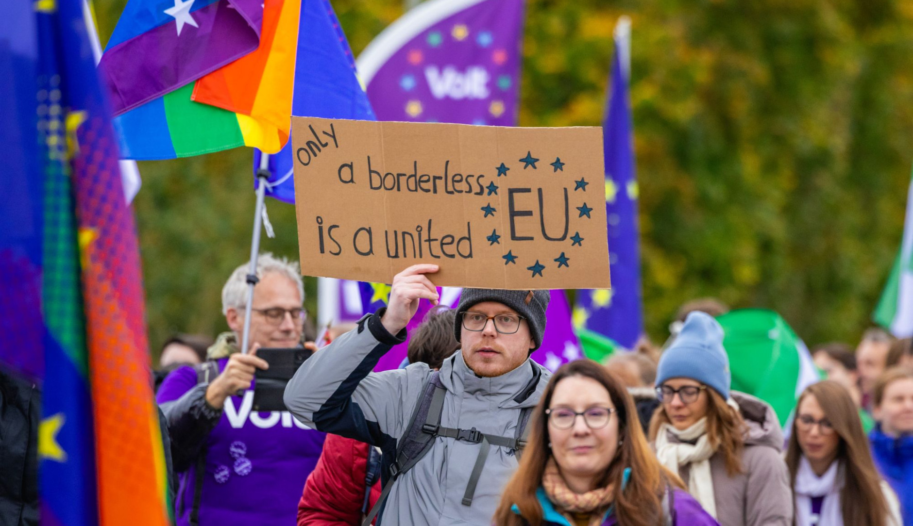 Foto einer Gruppe von Menschen mit Volt-Fahnen und einem Plakat