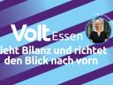 Grafik mit diagonalen lilafarbenen und hellblauen Streifen. In der Mitte steht der Text: Volt Essen zieht Bilanz und richtet den Blick nach vorn. Rechts oben ein rundes Porträtfoto mit dem Namen Mandy Hindenburg.