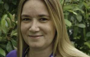 Profilaufnahme von Katharina Zelies, Stellv. Local Lead von Volt Frankfurt. Katharina steht vor einer grünen Hecke.