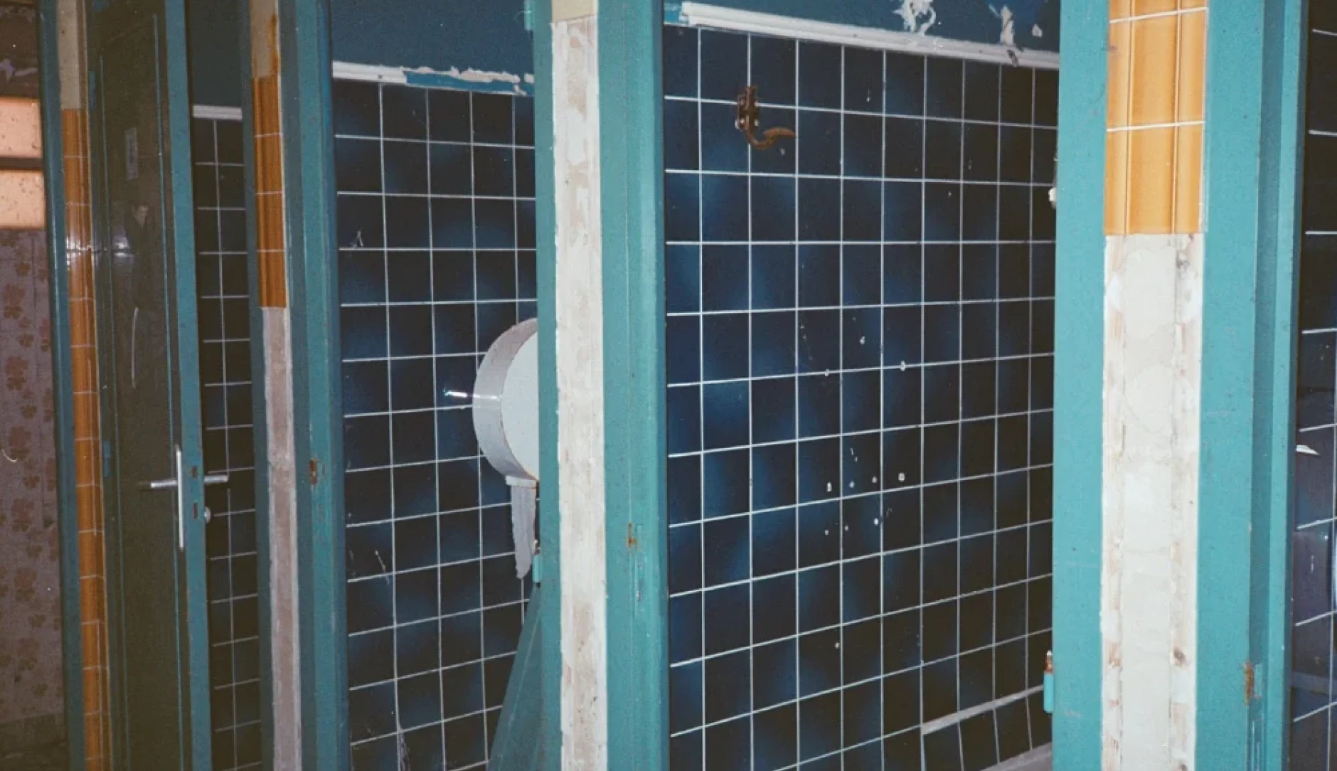 Es ist eine Schultoilette gezeigt, welche alte blaue Kacheln hat und Renovierung benötigt. Foto von yassine rahaoui auf Unsplash