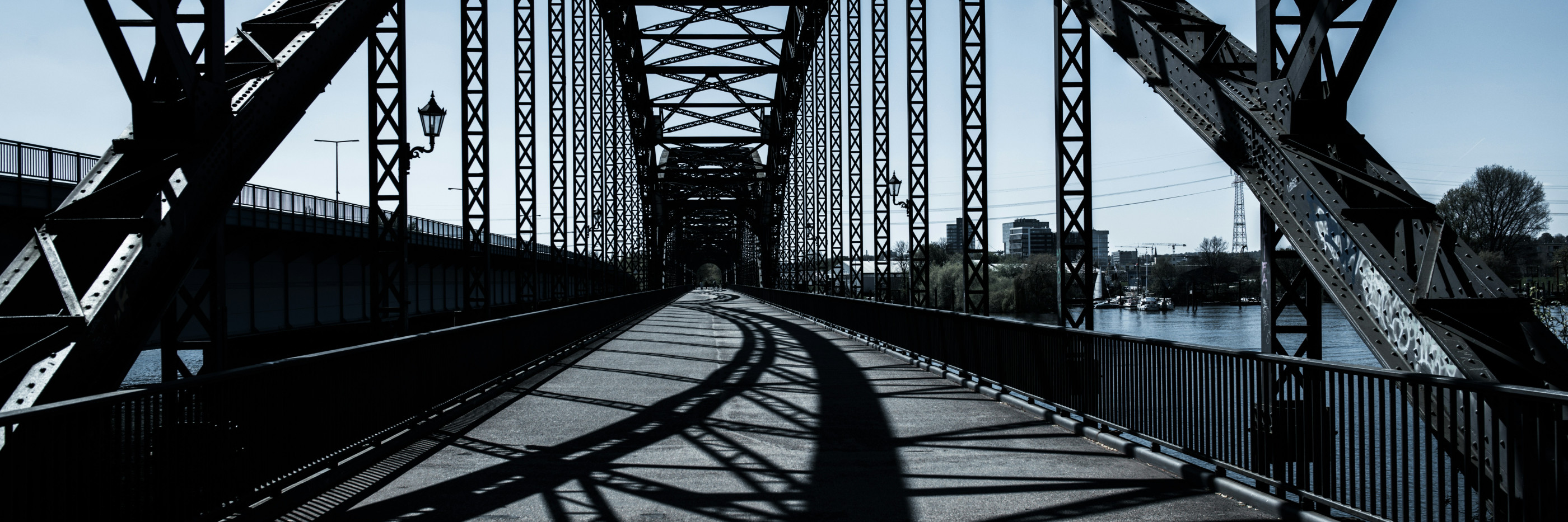 Wir sehen vor uns den Weg über eine mit verschiedenen Stahlträgern stabilisierte Brücke.