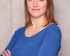 Kandidatin Sarah Veigel mit verschränkten Armen in einem blauen Pullover vor einer grauen Betonwand