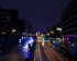 Willy Brandt Straße in Hamburg bei Nacht. In der Mitte ist eine beleuchtete Straße bei Nacht. Auf beiden Seiten links und rechts sind circa sechsstöckige Hochhäuser. Im Hintergrund ist eine Eisenbahnbrücke die von links nach rechts zieht. Die Schweinwerfer sind aufgrund einer Langzeitbelichtung über das Bild verschwommen