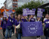 Viele jungen Menschen von Volt mit Lila Volt-Shirts. Im Vordergrund halten zwei Personen eine Flagge mit Volt Aufschrift und die Personen im hinteren Bereich halten Schilder hoch mit den Aufschriften: 