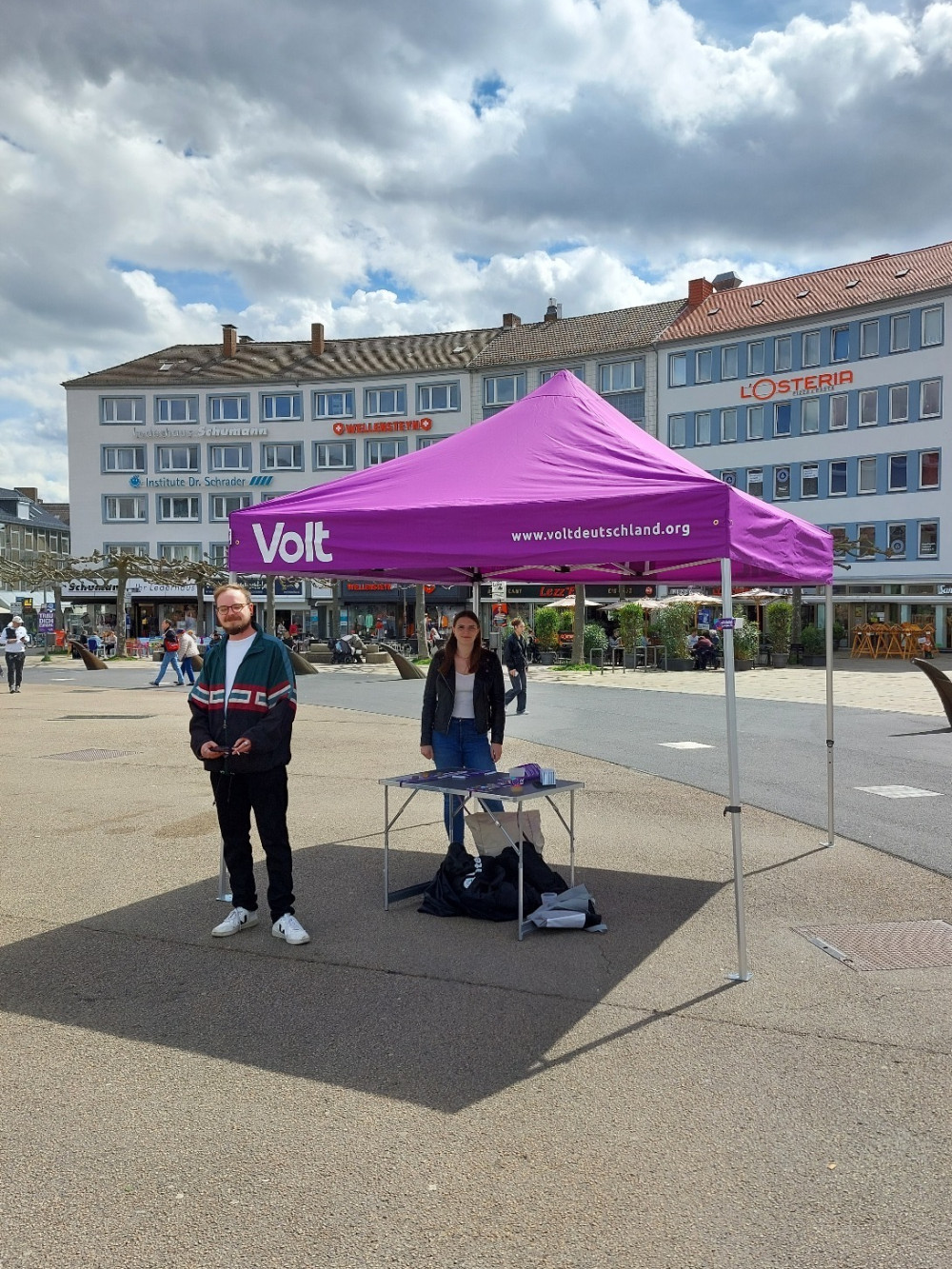 Bild des Kassler Infostandes am Königsplatz in Kassel mit Volt-Pavillion und zwei Personen des lokalen Kassler Volt teams