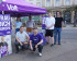 6 Mitglieder des Kassler Volt Teams am Stand am Königsplatz in Kassel. 2 knien vor dem Stand, 2 stehen daneben und 2 stehen unter dem Pavillion. Es sind auch Plakate für die Europawahl 2024 von Volt zu sehen.