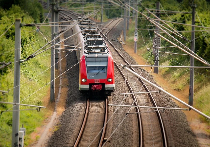 Zug der deutschen Bahn passiert unter einer Vielzahl von Oberleitungen eine Weiche