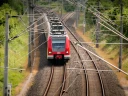 Zug der deutschen Bahn passiert unter einer Vielzahl von Oberleitungen eine Weiche