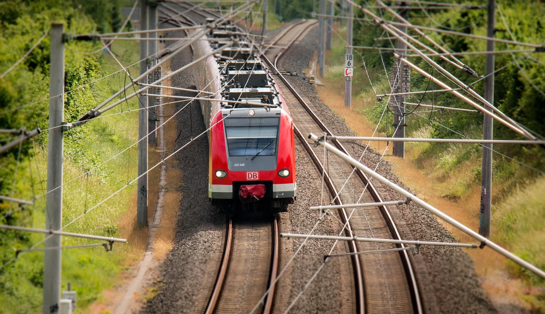 Zug der deutschen Bahn passiert unter einer Vielzahl von Oberleitungen eine Weiche