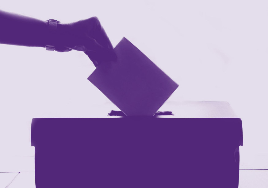 Wahlurne mit Hand darüber, die einen Wahlzettel einwirft. Alles ist lila.