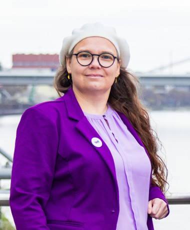 Portrait von Michaela am Rheinufer mit freundlichem, hoffnungsvollen Blick.