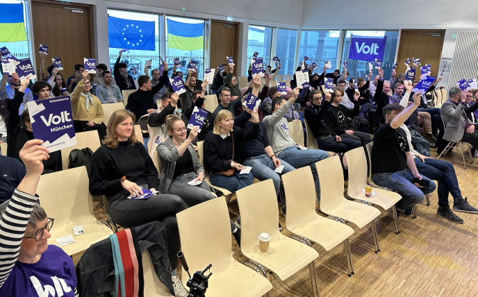 Foto auf dem Mitglieder von Volt München Stimmkarten hochhalten