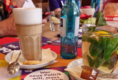 Kaffeetisch mit diversen Heißgetränken und Volt Mitgliedern im Hintergrund