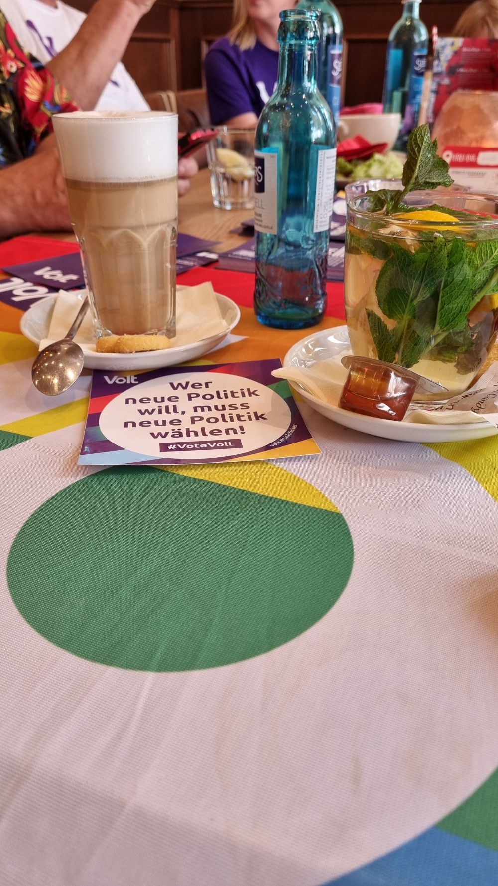 Kaffeetisch mit diversen Heißgetränken und Volt Mitgliedern im Hintergrund