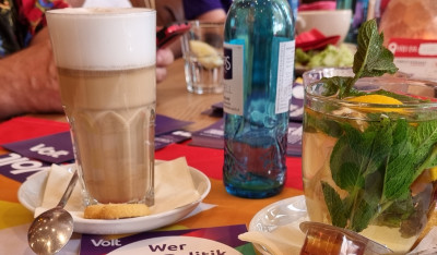 Kaffeetisch mit diversen Heißgetränken und Volt Mitgliedern im Hintergrund