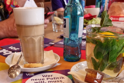 Kaffeetisch mit diversen Heißgetränken und Volt Mitgliedern im Hintergrund