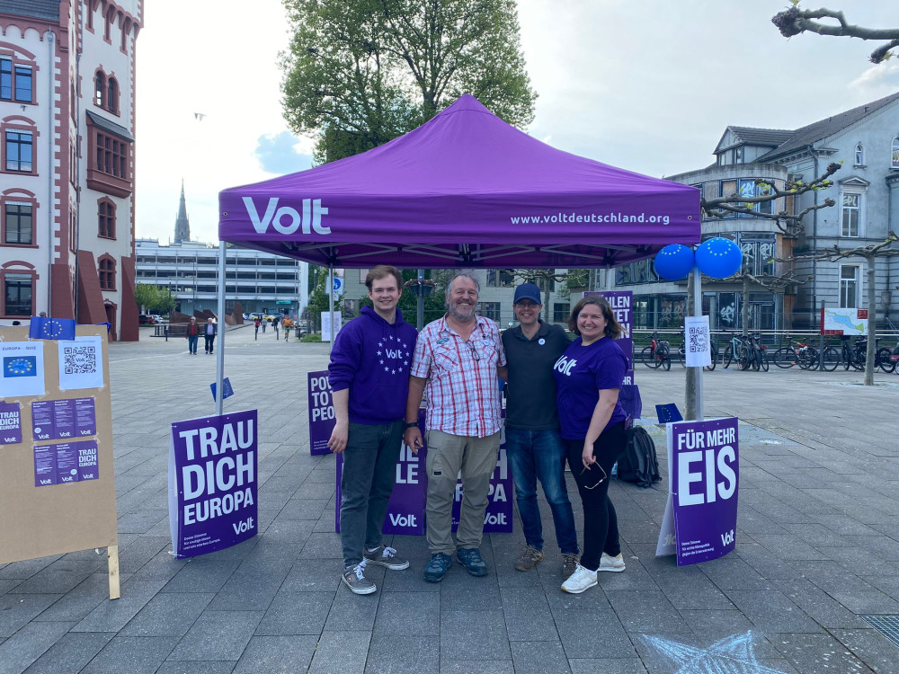 Volt Infostand zur Europawahl. An dem Pavillon stehen Plakate mit den Wahlsprüchen: 