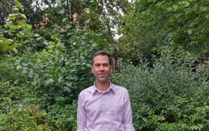 Julian Herrmann steht vor einem Busch.