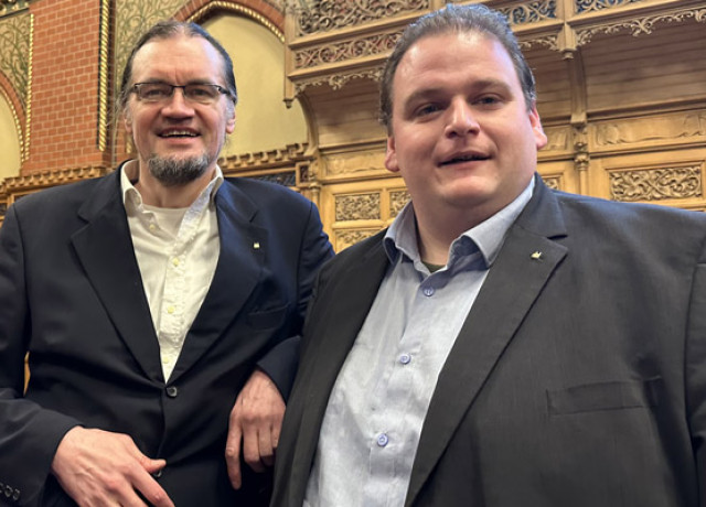 Tim Stüttgen und Gregor Voht stehen lächelnd im Lübecker Bürgerschaftssaal.