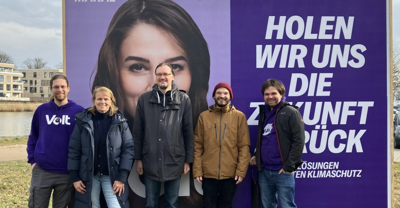 Volt Lübeck Team vor einem Maral Bundestagswahl Plakat.