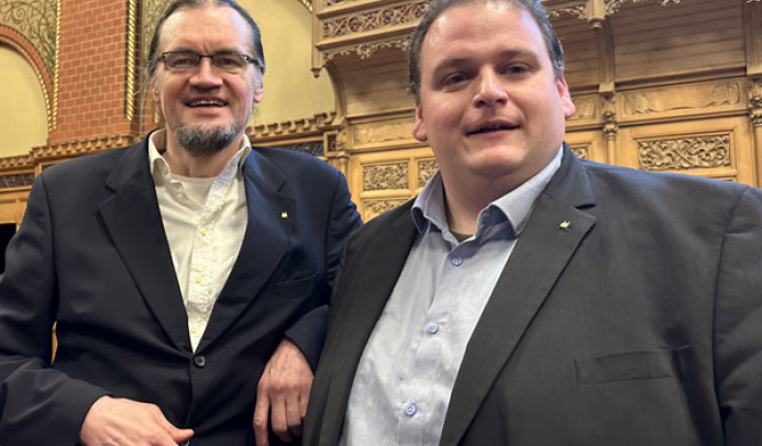 Tim Stüttgen und Gregor Voht stehen lächelnd im Lübecker Bürgerschaftssaal.