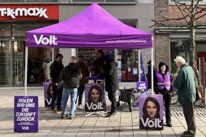 Menschen stehen verteilt am infostand und reden miteinander.