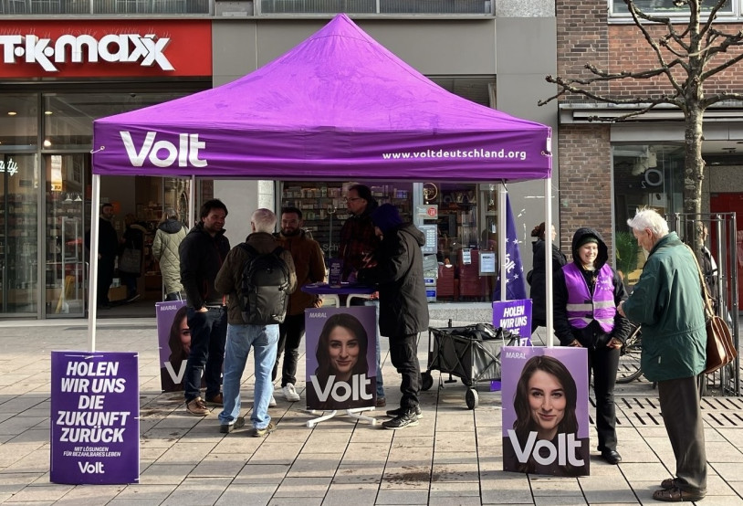 Menschen stehen verteilt am infostand und reden miteinander.