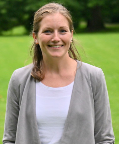 Kim Christin Holzmann steht lächelnd im Park.