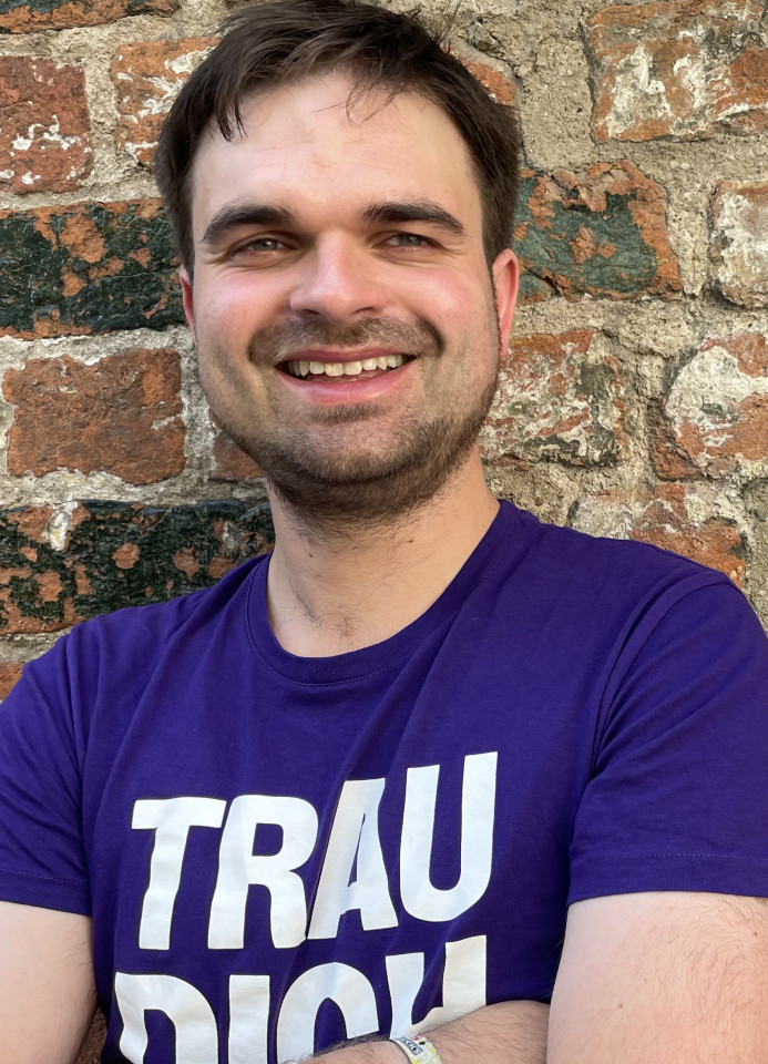 Martin Janßen steht im Volt T-Shirt vor einer Backsteinmauer.