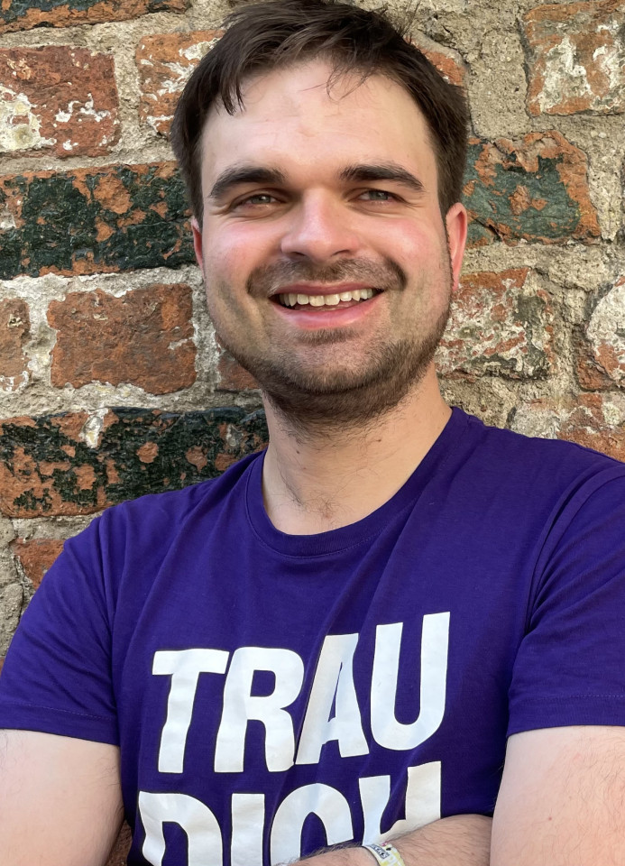 Martin Janßen steht im Volt T-Shirt vor einer Backsteinmauer.