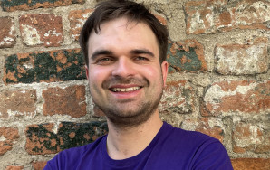 Martin Janßen steht im Volt T-Shirt vor einer Backsteinmauer.