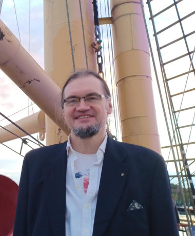 Tim Stüttgen sthet in einem Anzug for einem Mast.