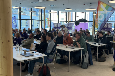 Die Mitglieder von Volt sitzen für den parteitag an Tischen.