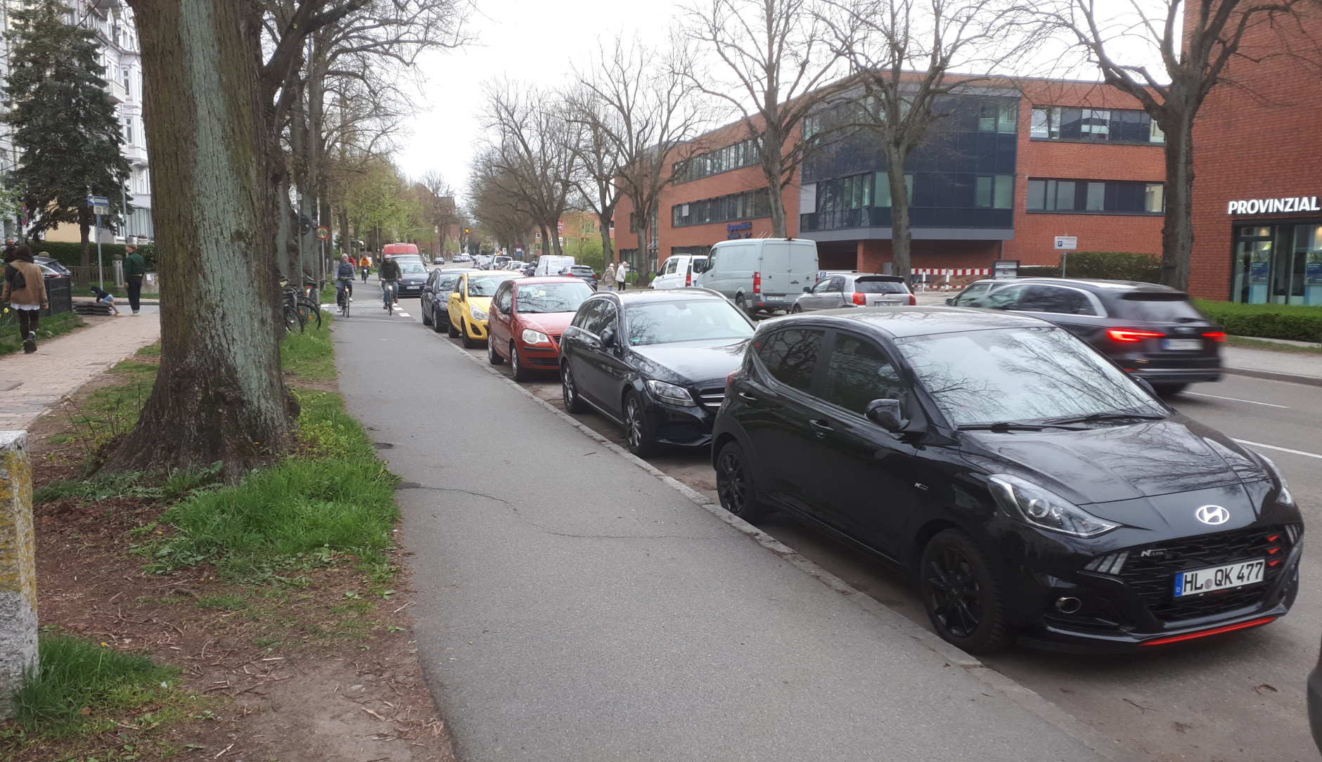 Ein Bild der Falkenstraße und des Radweg, mit Autos welche eine Spur zuparken.