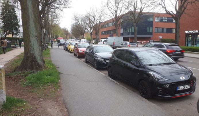 Ein Bild der Falkenstraße und des Radweg, mit Autos welche eine Spur zuparken.
